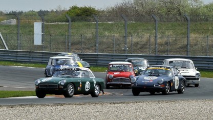 Enkele historische racewagens racend op Circuit Zandvoort, waaronder een MG B, Porsche 911 en enkele Mini's.
